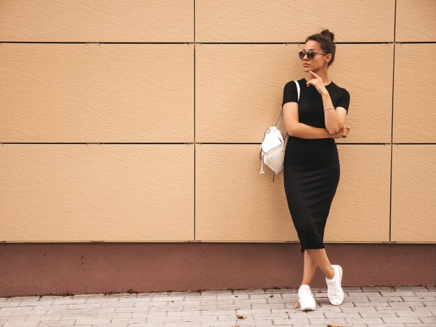 Retrato de hermosa modelo sonriente vestida con ropa de verano. Chica de moda posando en la calle. Mujer divertida y positiva divirtiéndose en gafas de sol