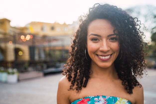 Retrato de hermosa mujer afroamericana Latina confiada riendo en la calle. Al aire libre.