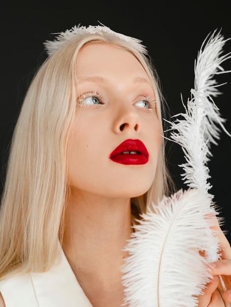 Retrato de hermosa mujer albina con pluma blanca