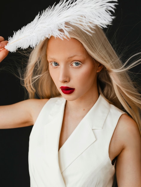 Retrato de hermosa mujer albina con pluma blanca