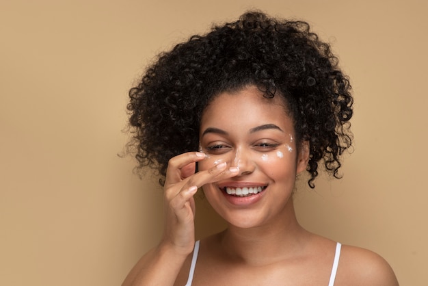 Retrato de una hermosa mujer aplicando crema hidratante en su rostro