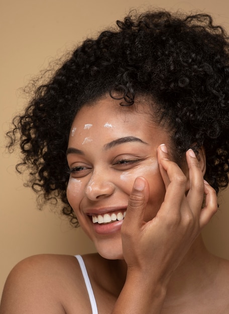 Retrato de una hermosa mujer aplicando crema hidratante en su rostro
