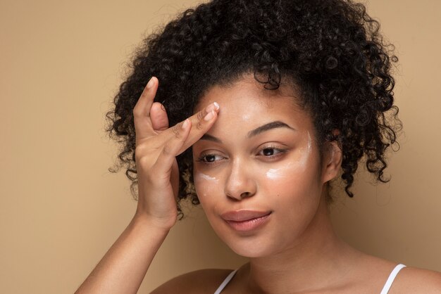 Retrato de una hermosa mujer aplicando crema hidratante en su rostro