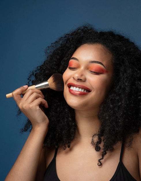 Retrato de una hermosa mujer aplicando maquillaje con un pincel de maquillaje