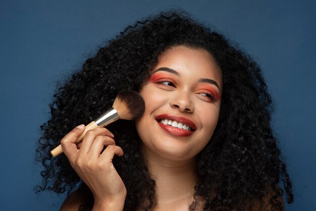 Retrato de una hermosa mujer aplicando maquillaje con un pincel de maquillaje