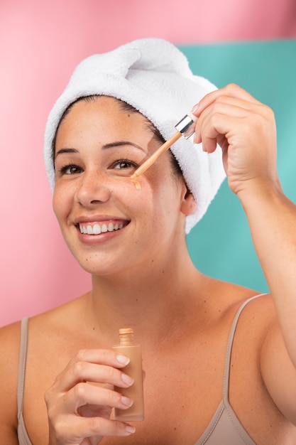 Retrato de una hermosa mujer aplicando suero en su rostro