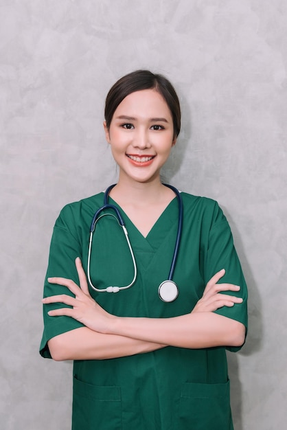 Foto gratuita retrato de una hermosa mujer asiática, doctora, trabajadora de la salud, de pie con los brazos cruzados, aislada de fondo gris