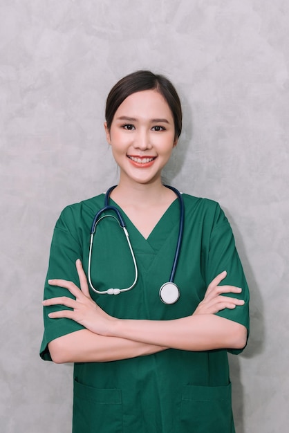 Retrato de una hermosa mujer asiática, doctora, trabajadora de la salud, de pie con los brazos cruzados, aislada de fondo gris