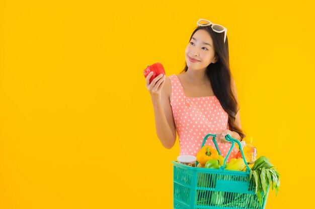 Retrato hermosa mujer asiática joven con comestibles en la cesta de compras del supermercado