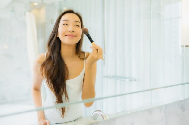 Retrato hermosa mujer asiática joven comprueba y compone su rostro