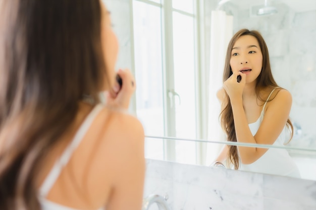 Retrato hermosa mujer asiática joven comprueba y compone su rostro