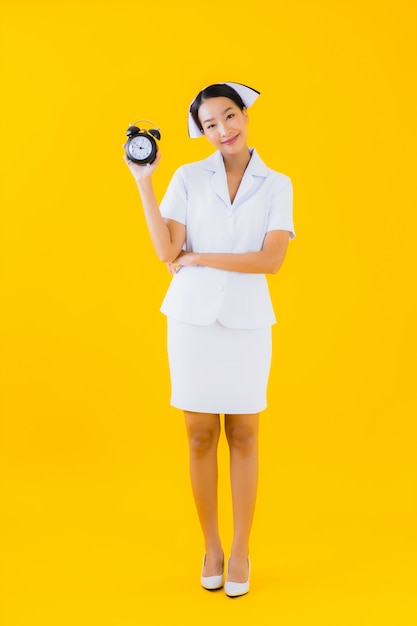 Retrato hermosa mujer asiática joven enfermera tailandesa con reloj o alarma