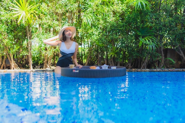 Retrato hermosa mujer asiática joven feliz sonrisa con desayuno flotante en bandeja en la piscina