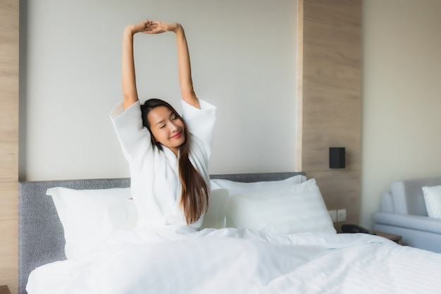 Retrato hermosa mujer asiática joven feliz sonrisa relajarse en la cama