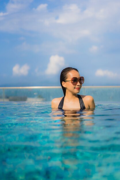 Retrato hermosa mujer asiática joven feliz sonrisa relajarse piscina al aire libre en el resort