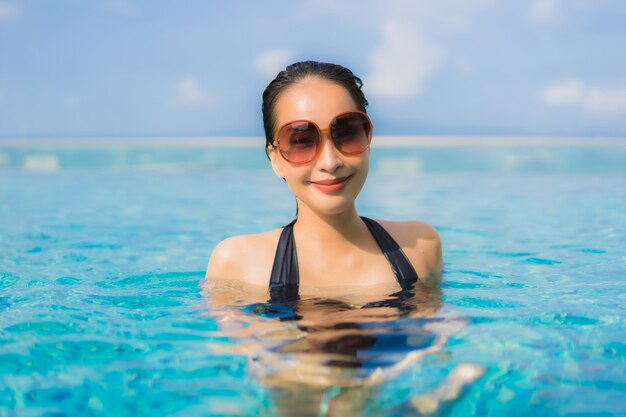 Retrato hermosa mujer asiática joven feliz sonrisa relajarse piscina al aire libre en el resort