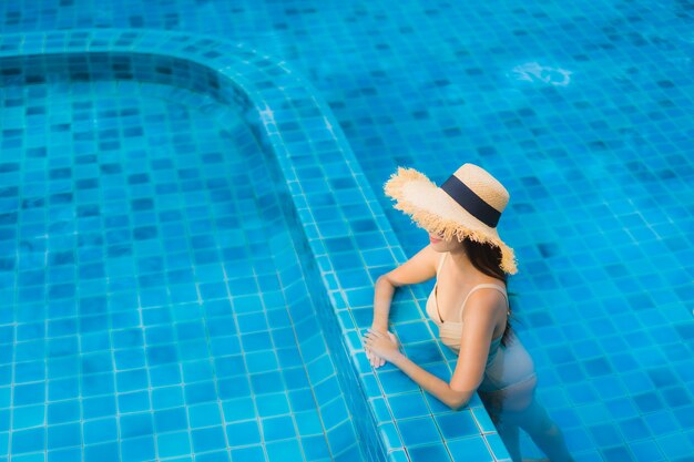 Retrato hermosa mujer asiática joven feliz sonrisa relajarse piscina al aire libre en el resort