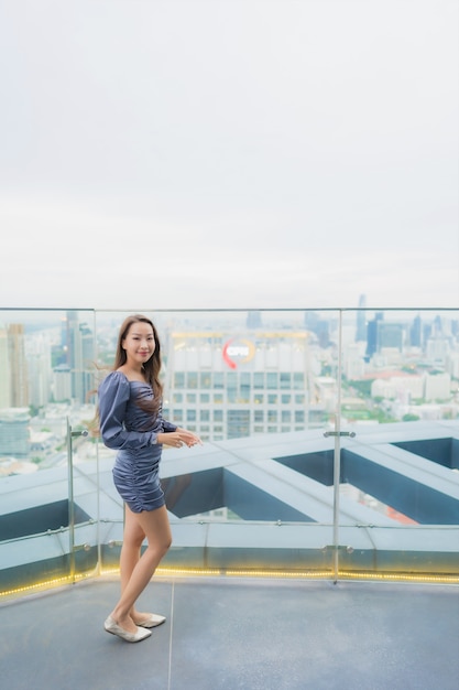 Retrato hermosa mujer asiática joven feliz sonrisa en el restaurante de la azotea alrededor de la vista de la ciudad