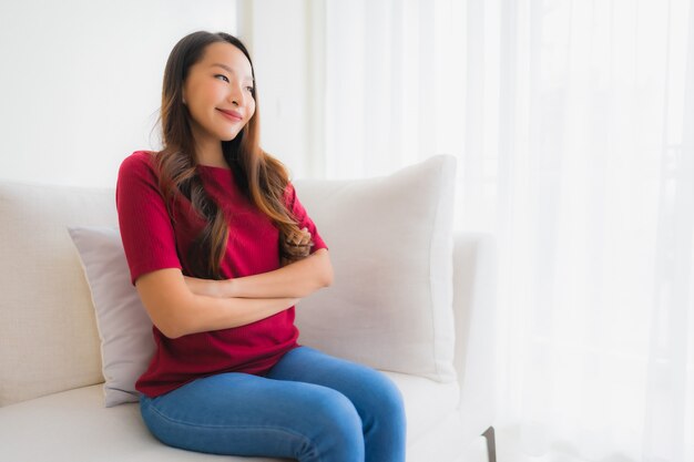 Retrato hermosa mujer asiática joven feliz sonrisa sentarse en el sofá