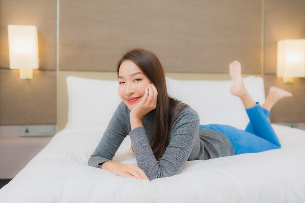 Retrato de hermosa mujer asiática joven se relaja en la cama en el dormitorio