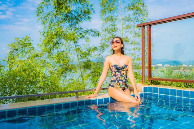 Foto gratuita retrato de hermosa mujer asiática joven relajante en la piscina al aire libre con vista al mar