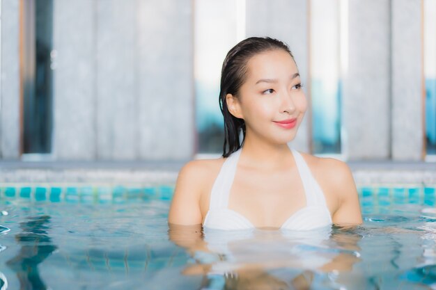 Retrato hermosa mujer asiática joven relajarse sonrisa alrededor de la piscina en el hotel resort en vacaciones traval