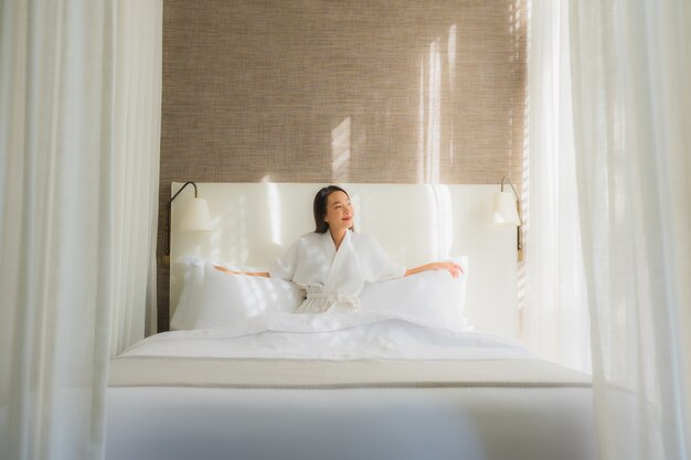 Retrato hermosa mujer asiática joven relajarse sonrisa en la cama en el dormitorio