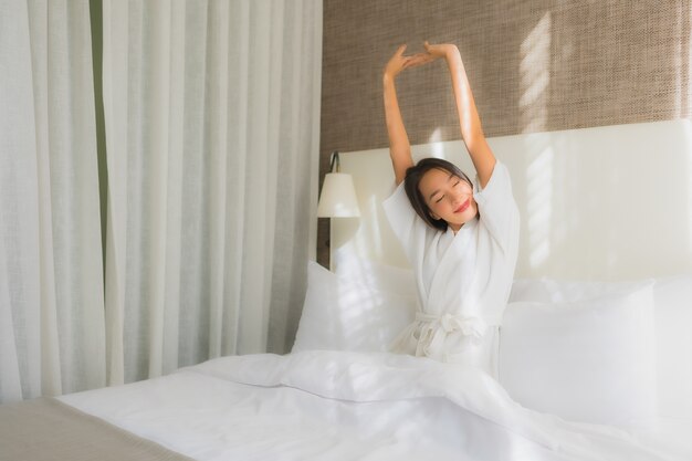 Retrato hermosa mujer asiática joven relajarse sonrisa en la cama en el dormitorio