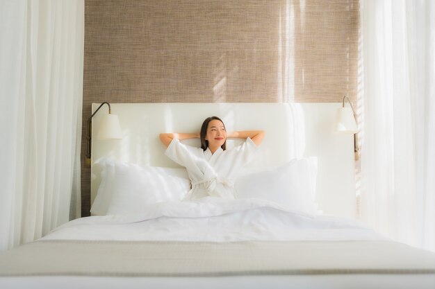 Retrato hermosa mujer asiática joven relajarse sonrisa en la cama en el dormitorio