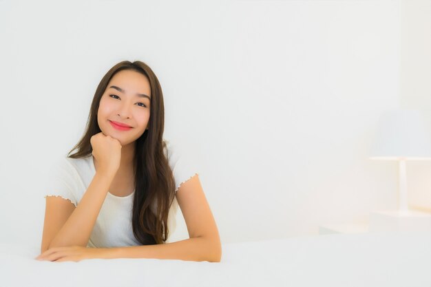 Retrato hermosa mujer asiática joven relajarse sonrisa feliz en la cama con una manta de almohada blanca