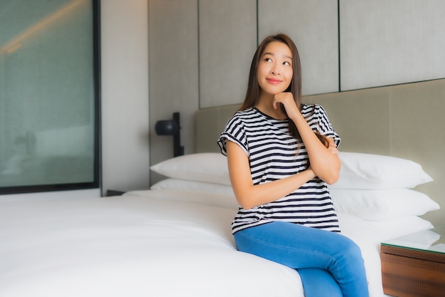 Retrato hermosa mujer asiática joven relajarse sonrisa feliz en el dormitorio