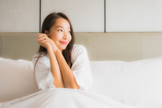 Retrato hermosa mujer asiática joven relajarse sonrisa feliz en el dormitorio