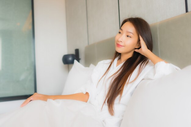 Retrato hermosa mujer asiática joven relajarse sonrisa feliz en el dormitorio