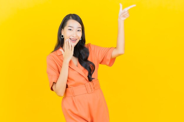 Retrato hermosa mujer asiática joven sonrisa con acción en amarillo