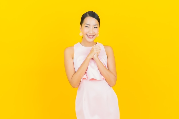 Retrato hermosa mujer asiática joven sonrisa con acción en amarillo