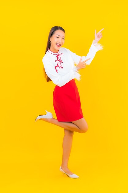 Retrato hermosa mujer asiática joven sonrisa en acción en amarillo