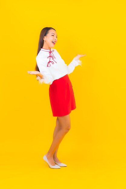 Retrato hermosa mujer asiática joven sonrisa en acción en amarillo