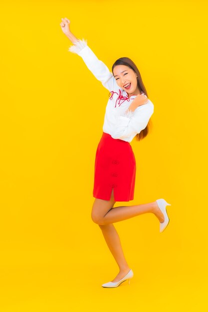 Retrato hermosa mujer asiática joven sonrisa en acción en amarillo