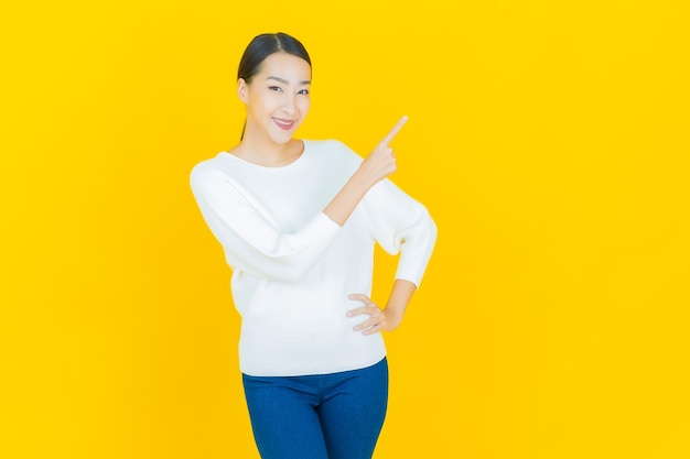 Retrato hermosa mujer asiática joven sonrisa con acción en amarillo