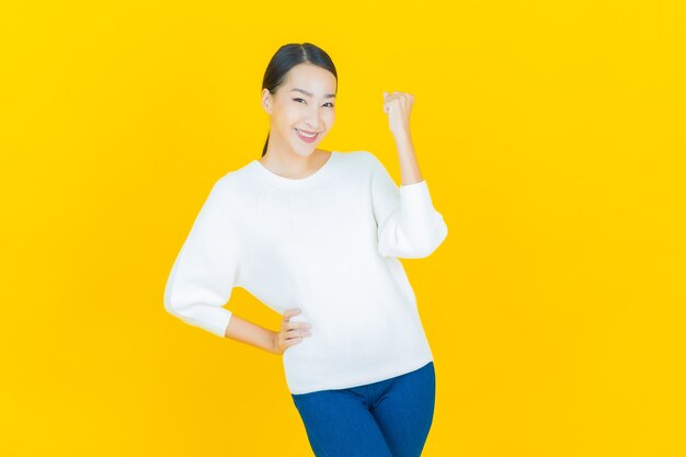 Retrato hermosa mujer asiática joven sonrisa con acción en amarillo