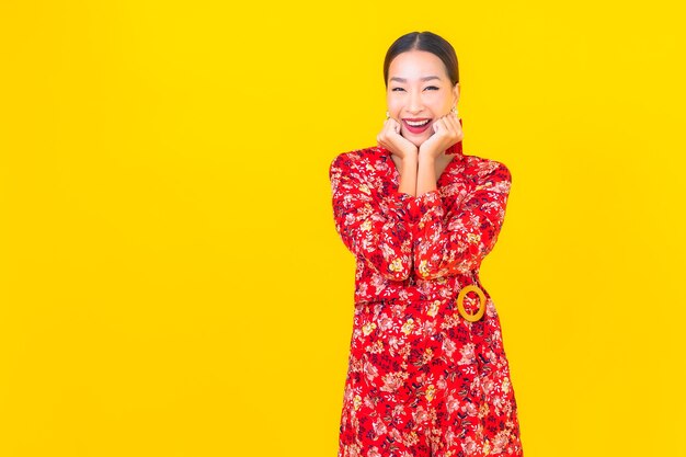 Retrato hermosa mujer asiática joven sonrisa en acción en concepto de año nuevo chino en la pared de color