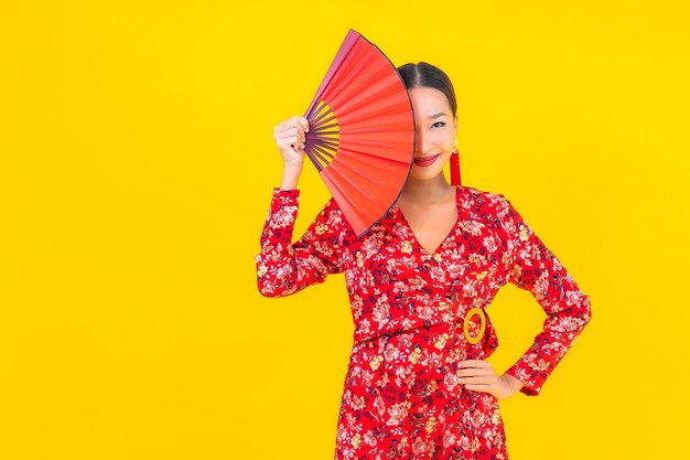 Retrato hermosa mujer asiática joven sonrisa en acción en concepto de año nuevo chino en la pared de color