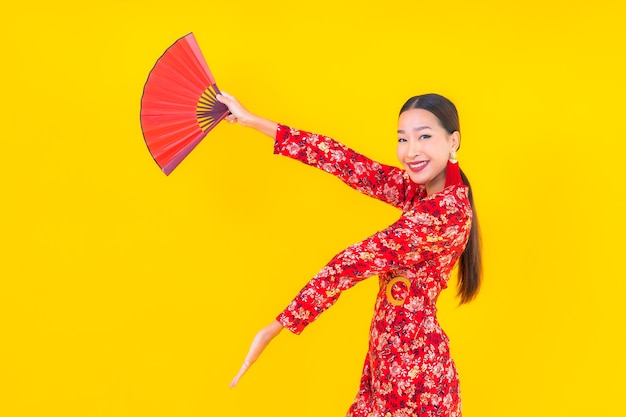 Retrato hermosa mujer asiática joven sonrisa en acción en concepto de año nuevo chino en la pared de color