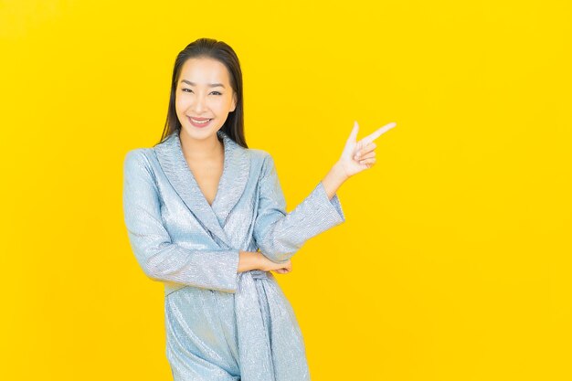 Retrato hermosa mujer asiática joven sonrisa con acción en la pared amarilla