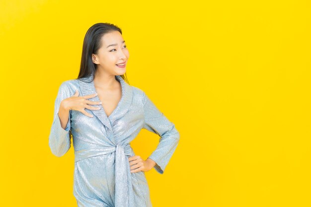 Retrato hermosa mujer asiática joven sonrisa con acción en la pared amarilla