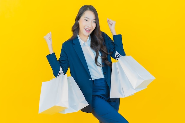 Retrato hermosa mujer asiática joven sonrisa con bolsa de compras en amarillo