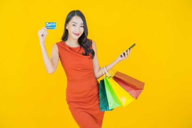 Retrato hermosa mujer asiática joven sonrisa con bolsa de compras en amarillo