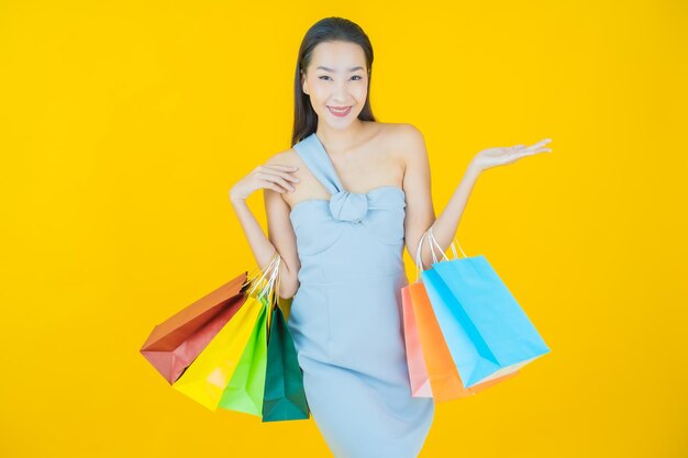 Retrato hermosa mujer asiática joven sonrisa con bolsa de compras en amarillo