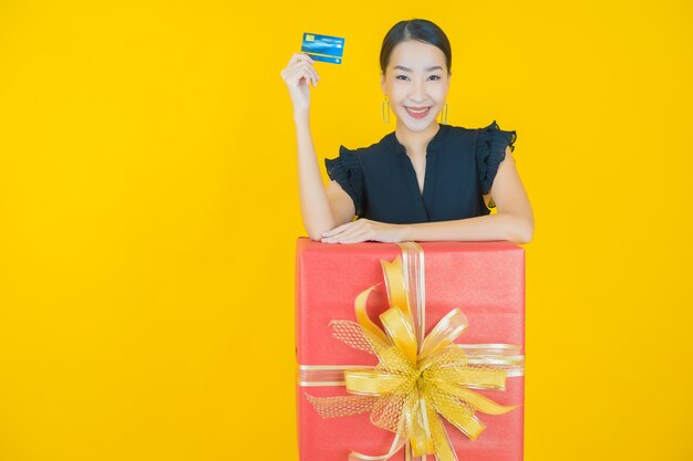 Retrato hermosa mujer asiática joven sonrisa con caja de regalo roja en amarillo
