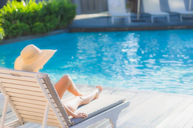 Retrato hermosa mujer asiática joven sonrisa feliz relajarse alrededor de la piscina al aire libre en el hotel resort